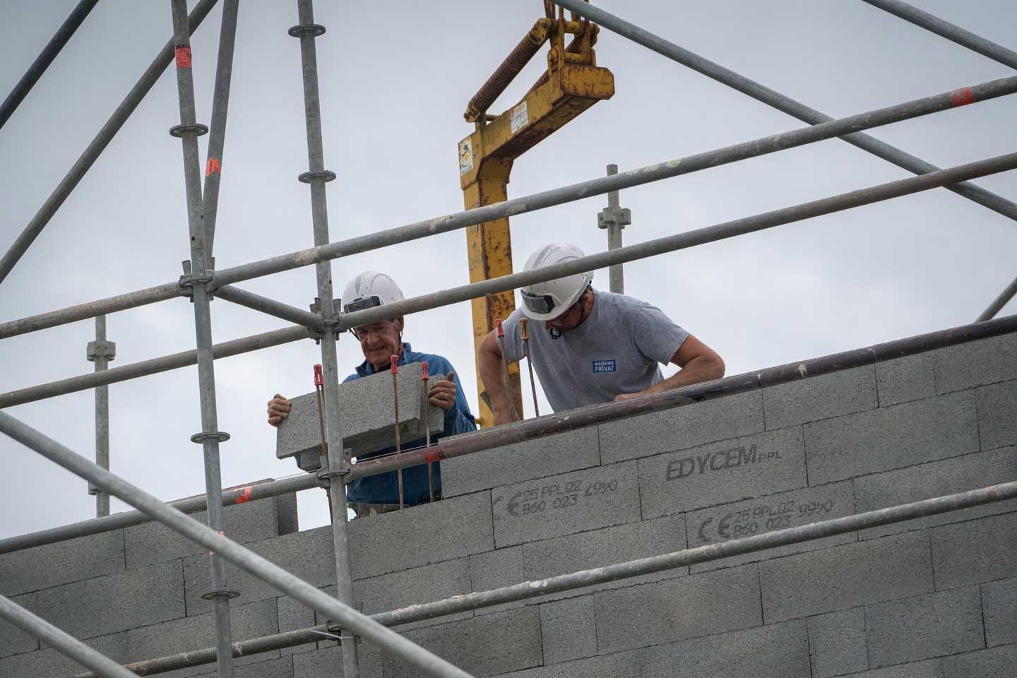 Deux ouvriers montent un mur sur un chantier de mainson individuelle.