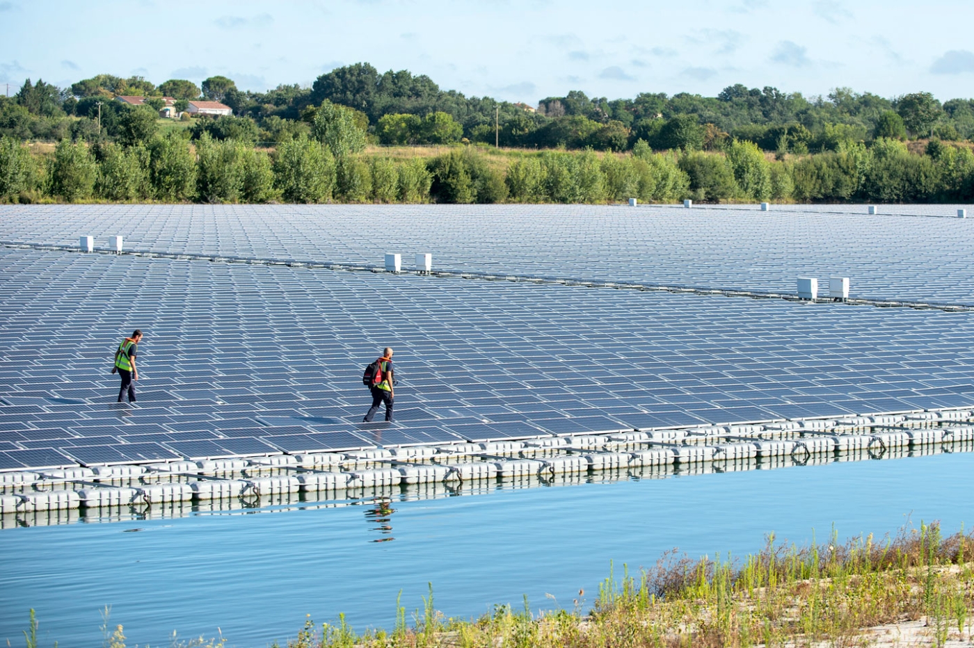 Deux salariés d'Urbasolar assurent la maintenance d'un parc photovoltaique flottant.