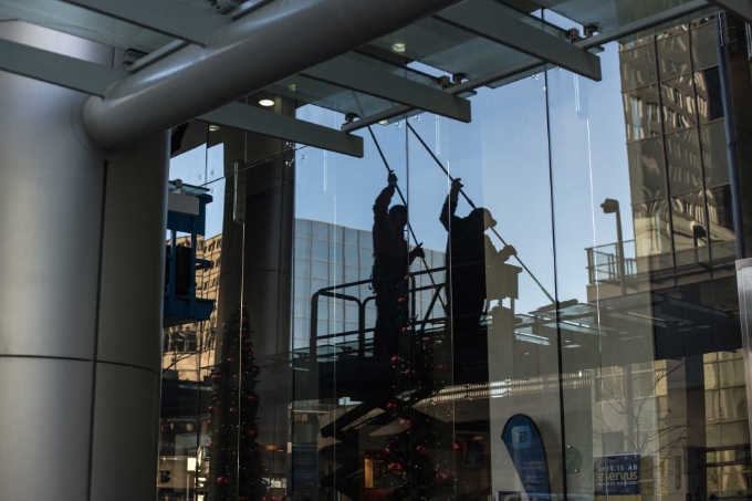 Un salarié sur une nacelle nettoie les vitres d'un bâtiment. 