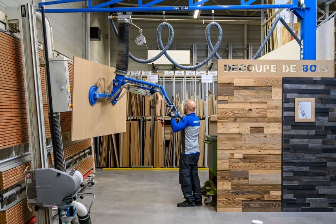 Un salarié utilise un préhenseur à ventouses dans l'atelier découpe de bois. Un salarié utilise un préhenseur à ventouses dans l'atelier découpe de bois.