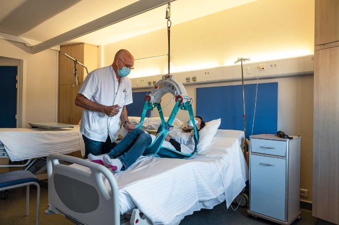 Un soignant utilise un lève-personne pour déplacer un patient.