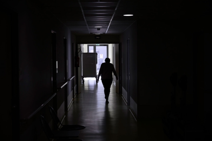 Un salarié marche dans un couloir sombre.
