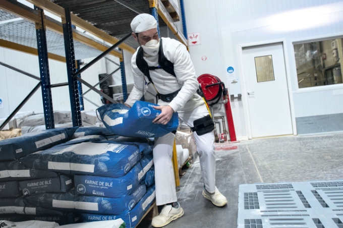 Un salarié équipé d'un exosquelette porte un sac de farine.