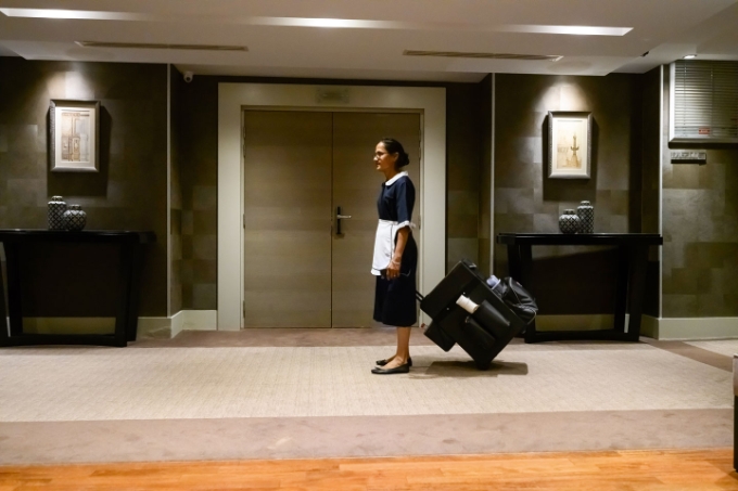 Une salariée d'un hôtel équipée d'une valise roulante dans le lobby d'un hôtel.