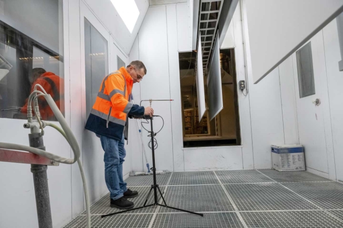 Fixation d'un anémomètre sur un trépied dans une cabine de peinture.