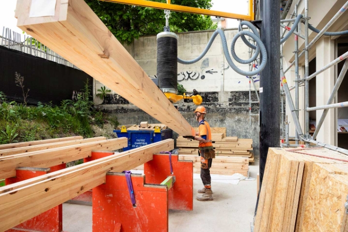 Un atelier de préfabrication des planchers en bois a été aménagé sur le site. Un préhenseur à ventouses sur potence aide à la manutention  des solives.
