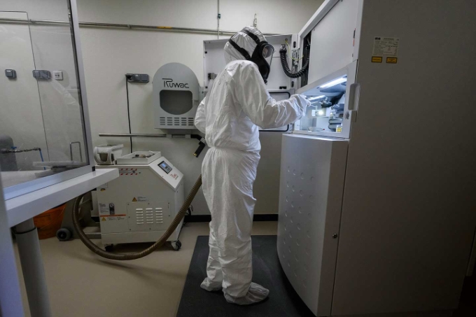 Avant de lancer un programme de fabrication de prothèse, la prothésiste aspire les résidus de poussières métalliques autour de l'imprimante laser.